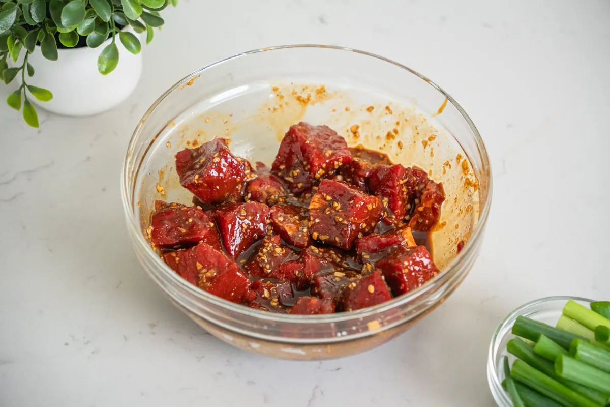 A bowl of beef being marinaded.