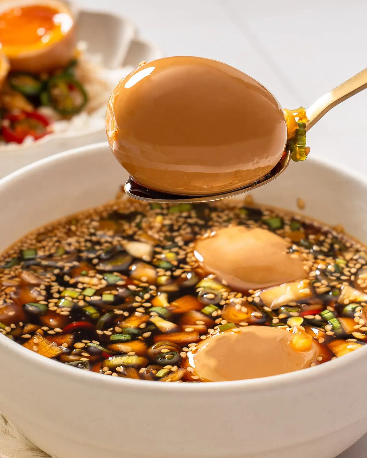 A mayak egg being lifted from a bowl with a spoon.