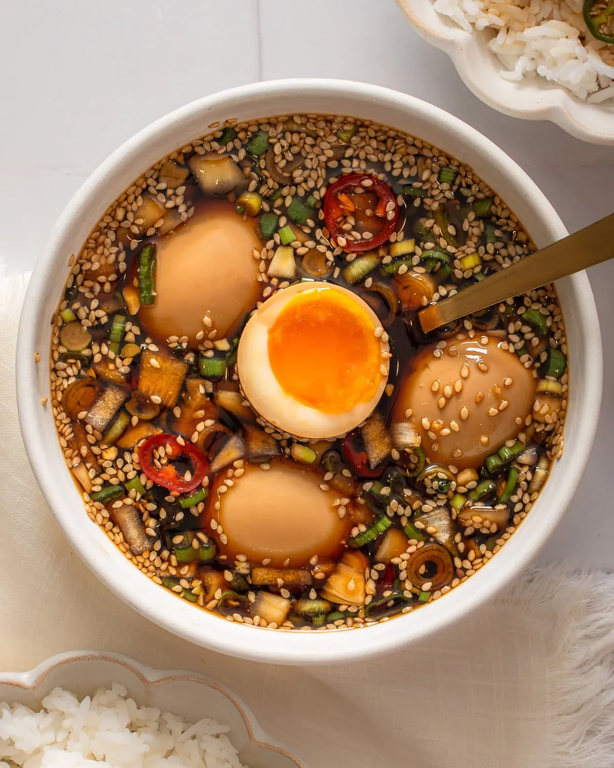 A cut open mayak egg being lifted from a bowl of eggs.