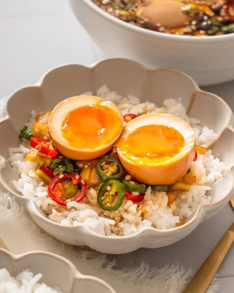 A bowl of rice topped with a sliced open mayak egg.