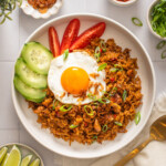 An overhead view of a plate of nasi goreng surrounded by table settings.