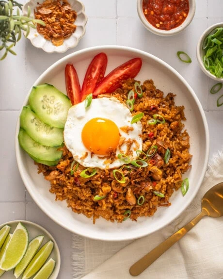 An overhead view of a plate of nasi goreng surrounded by table settings.