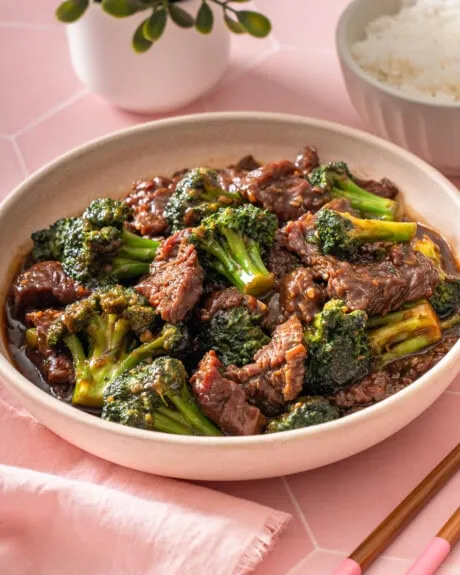 A plate of Chinese beef and broccoli on a tiled table.