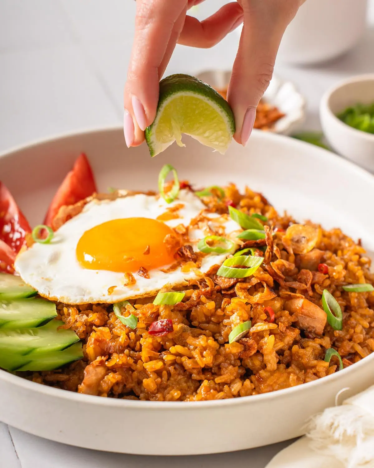 Squeezing a lime onto a plate of nasi goreng.