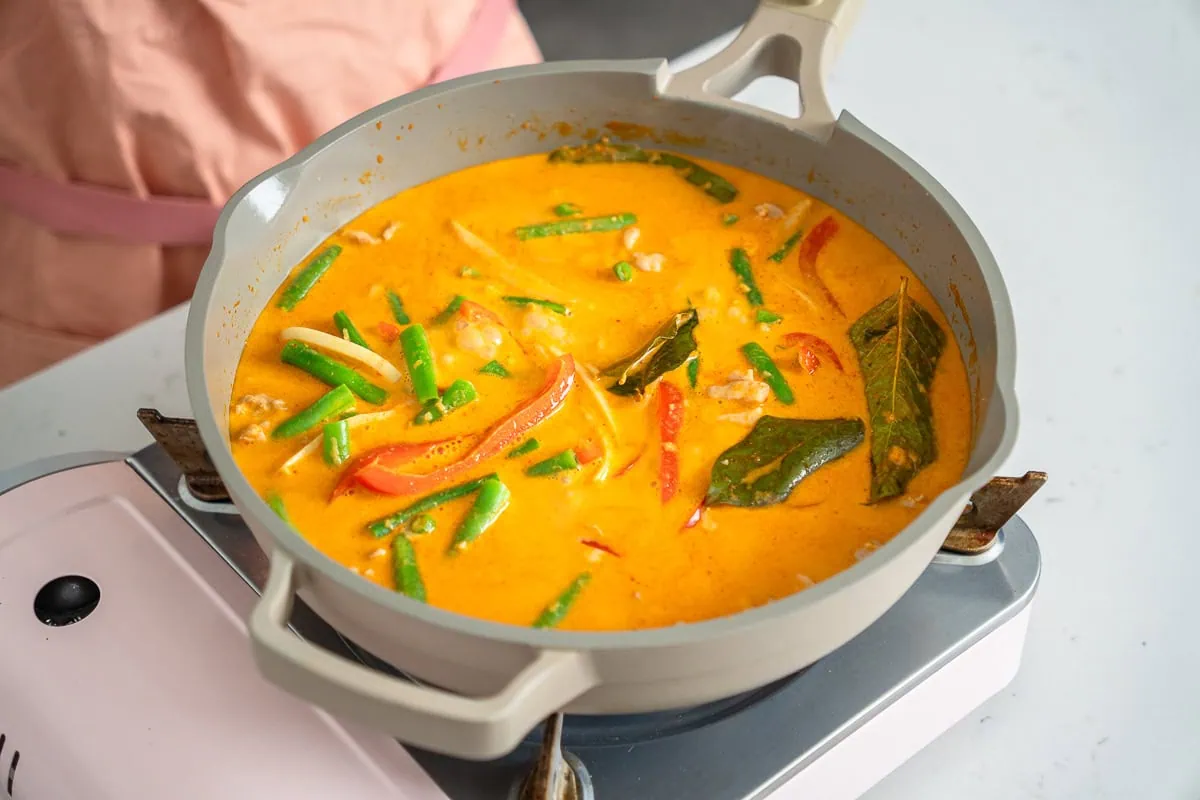 Thai red curry simmering in a large skillet.