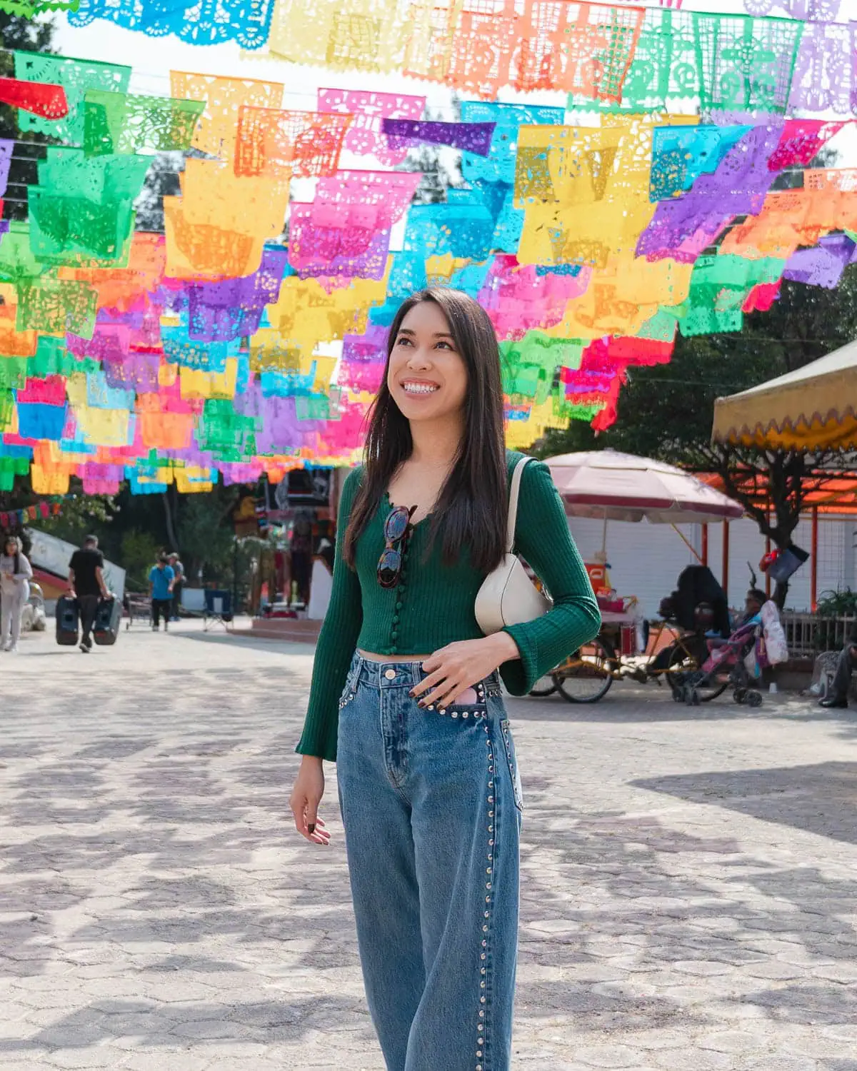 A girl standing under Mexican papel picado for a portrait.