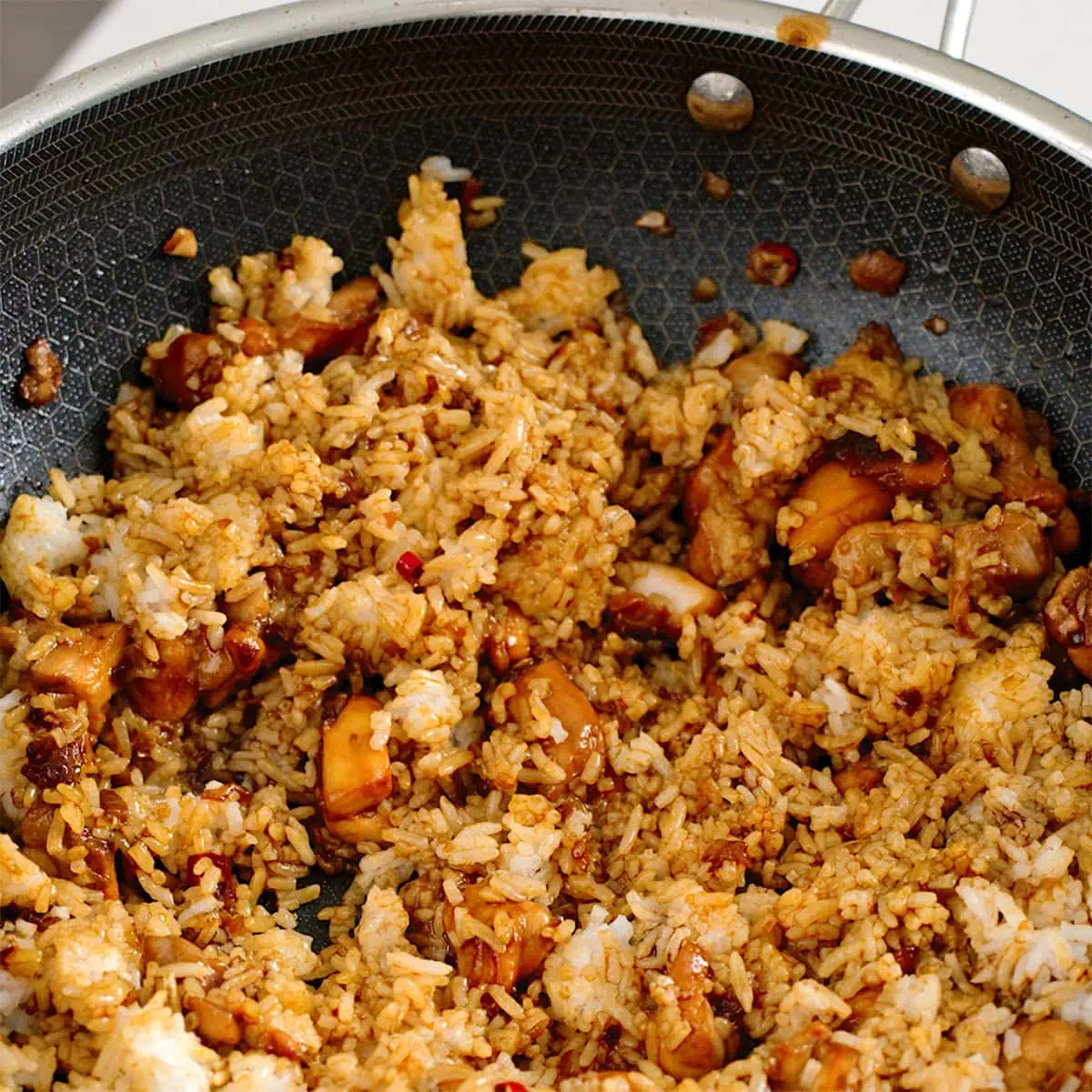 Rice and sauce tossed with chicken in a large wok.