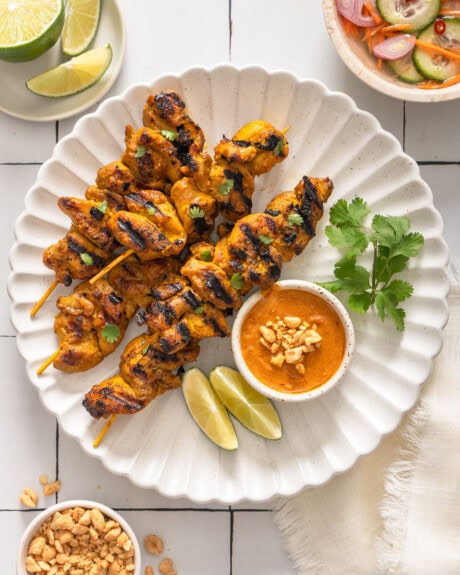 A top down view of a plate of Thai chicken satay skewers.