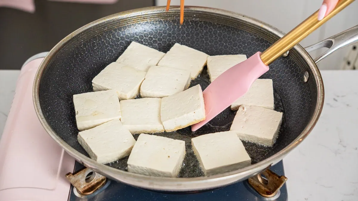 Searing sliced tofu in a skillet.